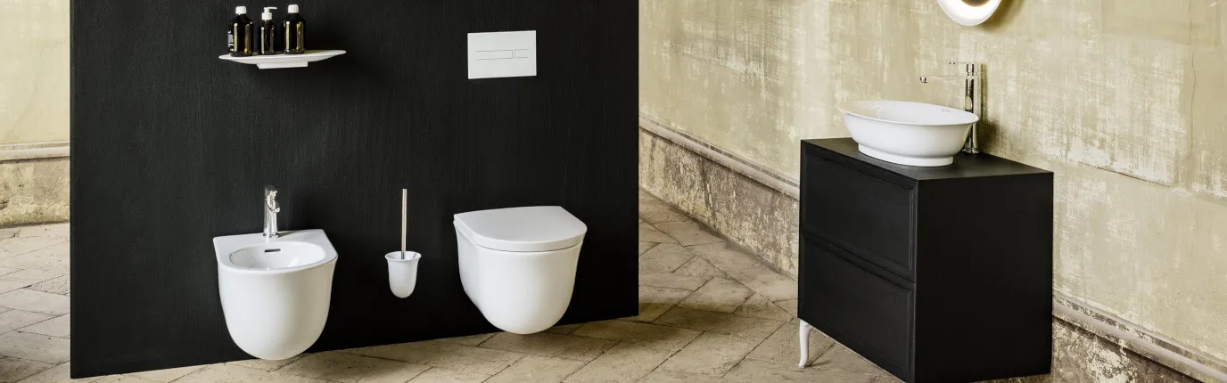 Ein modernes Badezimmer mit einer freihängenden Toilette und einem Bidet, beide an einer schwarzen Trennwand montiert.