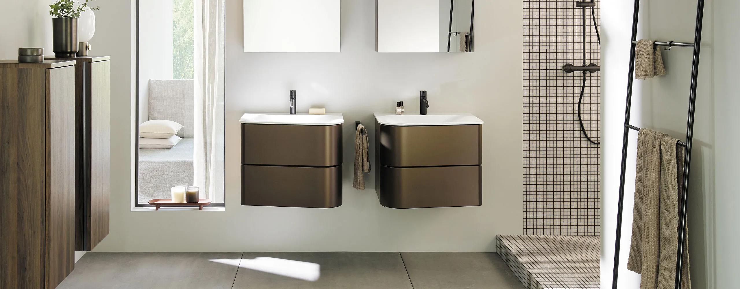 Ein Badezimmer mit zwei Waschtischen der Burgbad Badu-Serie, die jeweils schwarze Wasserhähne und zwei Schubladen haben.