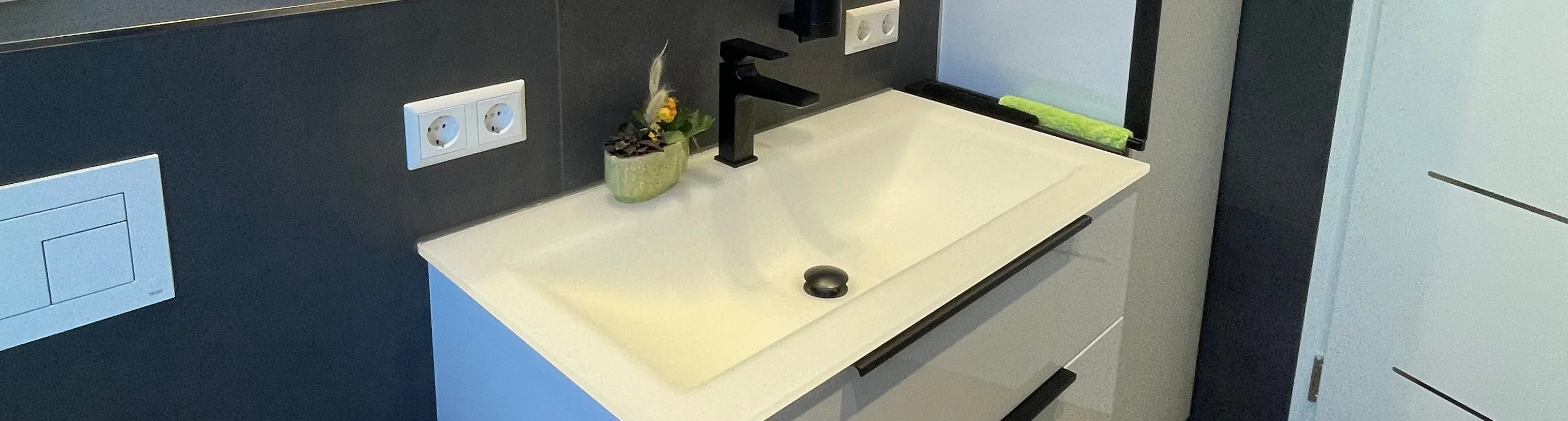 Ein modernes Badezimmer mit einem weißen Waschtisch mit zwei großen Schubladen und einem schwarzen Wasserhahn.