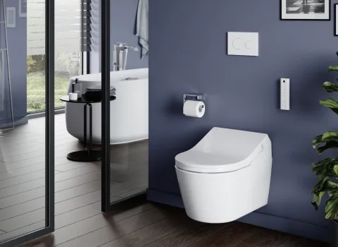 Ein elegantes Badezimmer mit einem wandmontierten weißen WASHLET vor einer dunkelblauen Wand.  