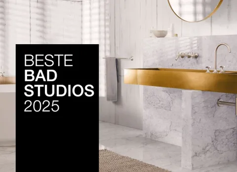 Ein stilvolles Bad mit goldenen Armaturen, Marmorwaschtisch und freistehender Badewanne. Ein schwarzer Banner mit "Beste Badstudios 2024" ist prominent im Bild.