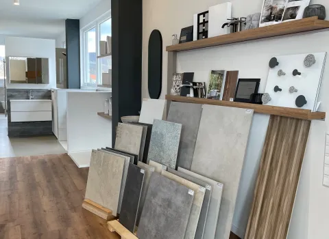 Die Aufnahme zeigt einen modernen Ausstellungsraum mit einer Auswahl an großformatigen Fliesenmustern in verschiedenen Grautönen.