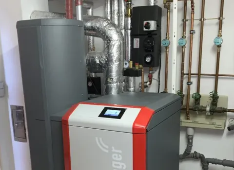 Moderne Heizungsanlage mit isolierten Rohrleitungen und Steuerungseinheit im Technikraum.
