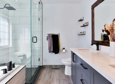 Modernes Badezimmer mit Glasdusche, Doppelwaschtisch, Holzrahmenspiegel und hellen Fliesen der Firma KDS Haustechnische Anlagen GmbH.