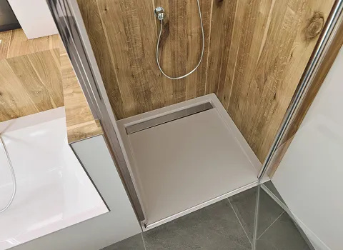 Bodengleiche Duschwanne vom Hersteller HSK aus weißem Acryl mit Ablaufrinne aus poliertem Edelstahl.