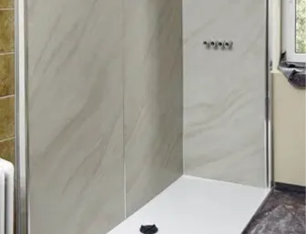 Badezimmer während der Sanierung: Die Dusche nimmt Form an. Die Wände sind jetzt mit großen, hellgrau marmorierten Wandpaneelen verkleidet, die eine glatte, moderne Oberfläche bilden.