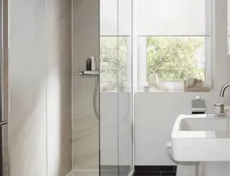 Modernes, fertig renoviertes Badezimmer mit großzügiger, bodenebener Dusche. Die Dusche hat eine transparente Glas-Schiebetür und helle, marmorierte Wandpaneele.