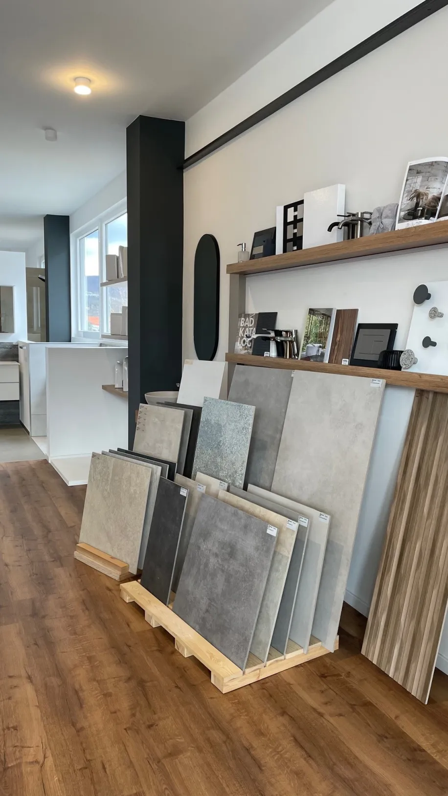 Die Aufnahme zeigt einen modernen Ausstellungsraum mit einer Auswahl an großformatigen Fliesenmustern in verschiedenen Grautönen.