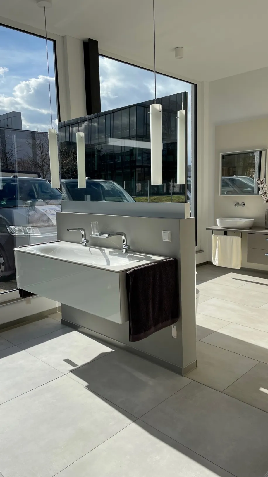 Ein großzügiger Ausstellungsraum mit großen Fensterfronten zeigt ein modernes Doppelwaschbecken mit schwebendem Unterschrank. 