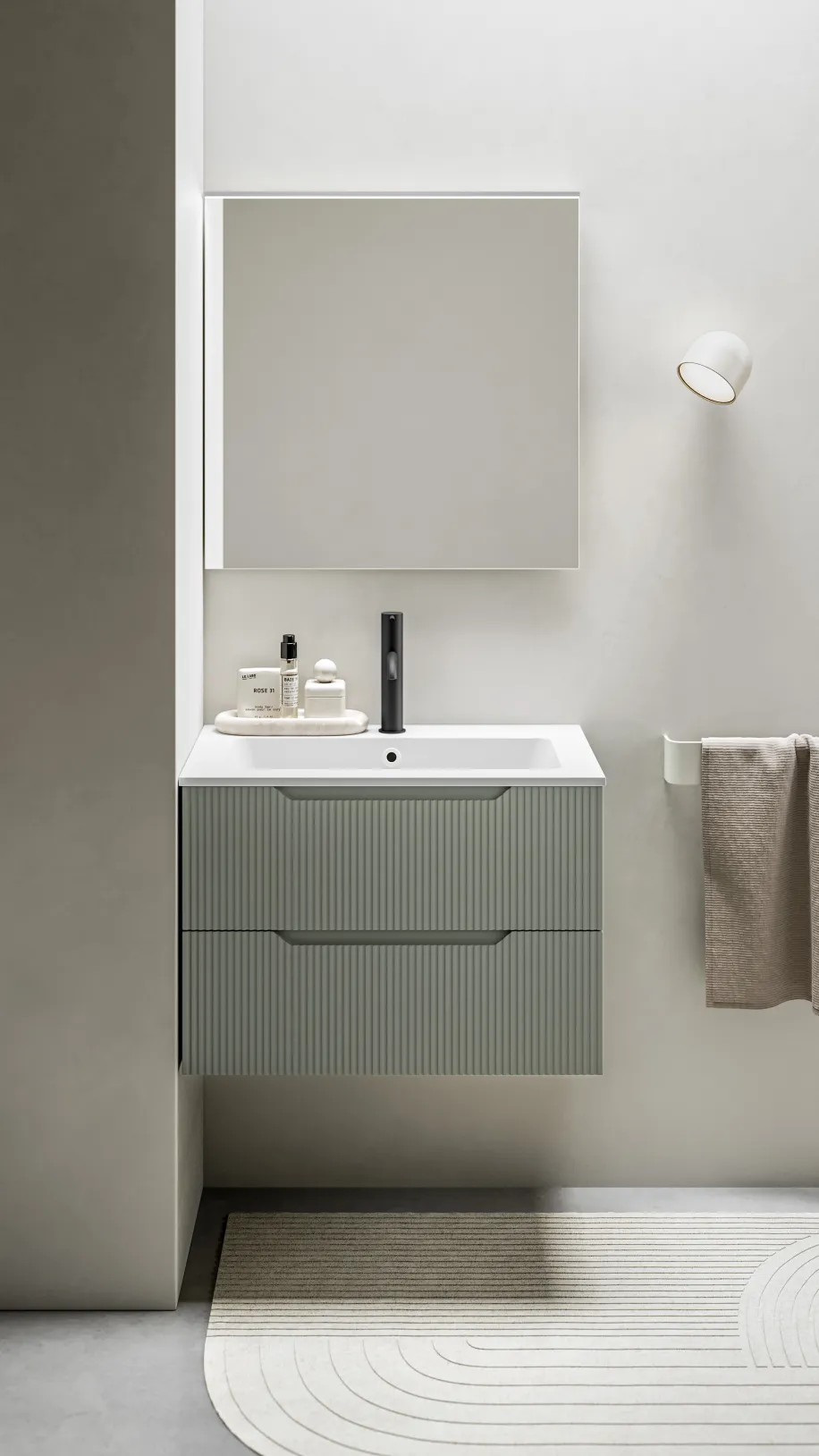 Kompakter, wandhängender Waschtisch mit geriffelter Front in Salbeigrün, weißem Becken und schwarzer Armatur.