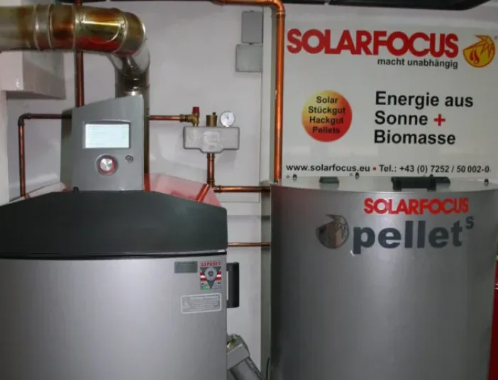 Pelletheizung und Pufferspeicher von SOLARFOCUS mit Rohrleitungen im Heizungsraum.