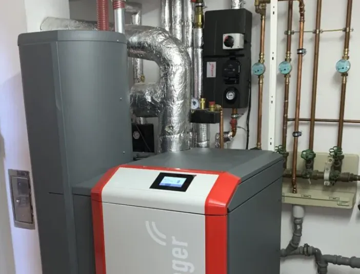 Moderne Heizungsanlage mit isolierten Rohrleitungen und Steuerungseinheit im Technikraum.