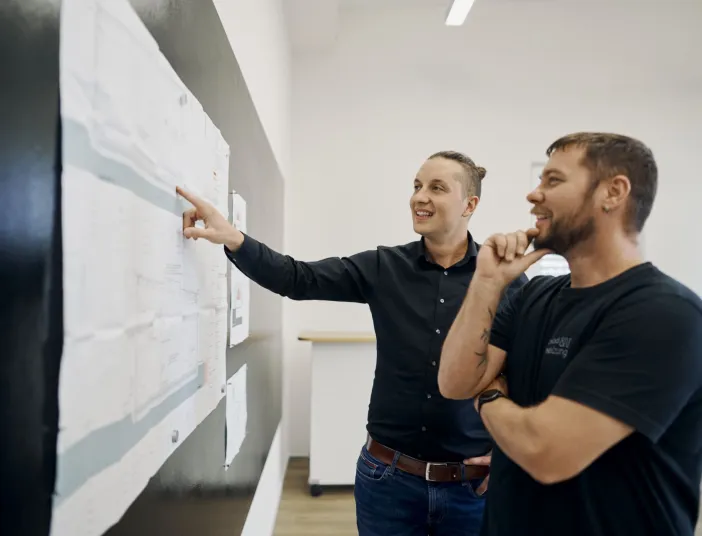 Projektleiter und Anlagenmechaniker im SHK-Handwerk besprechen die Planzeichnung eines Sanierungsprojektes. 