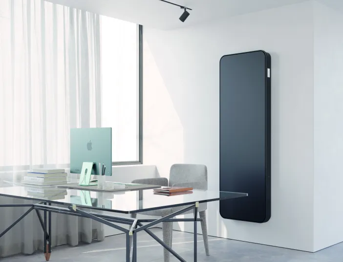 Vertikaler schwarzer Designheizkörper Relax Hybrid im modernen Büro.